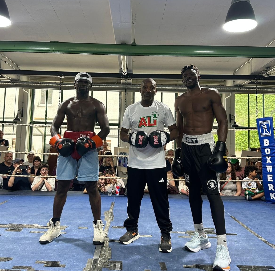 Coach Walu in the ring between two professional boxers at Boxwerk Munich